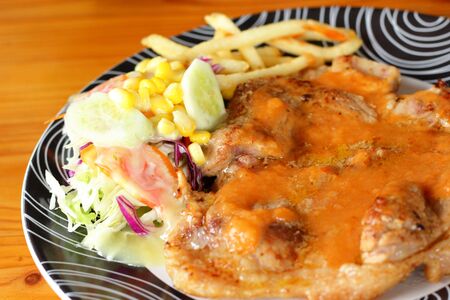 Steaks, french fries with vegetables salad on a plate.の写真素材