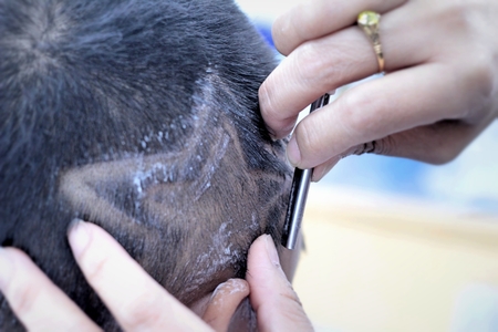 The boy's haircut with clipper and razor in the barber shopの写真素材