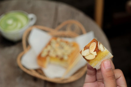 Toast topped with almonds and honey in hand
