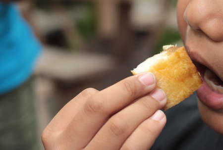 The boy eating toast topped with almonds and honey.の写真素材