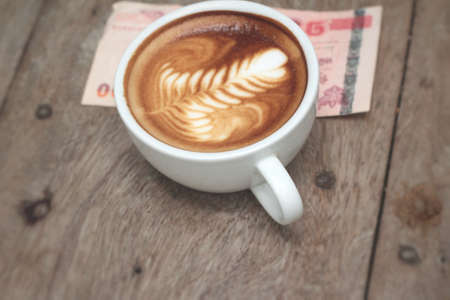 latte coffee in cup and banknoteの写真素材
