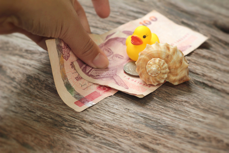 yellow rubber duck and banknotes ,coins on wood backgroundの写真素材