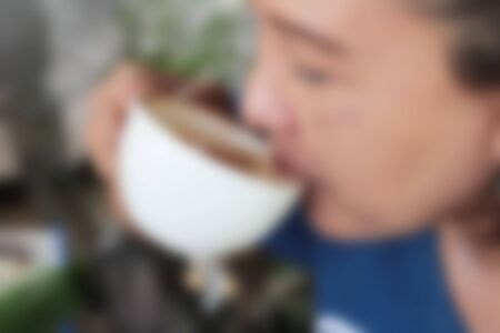 Blurred woman eating a hot latte coffee in glass.の写真素材