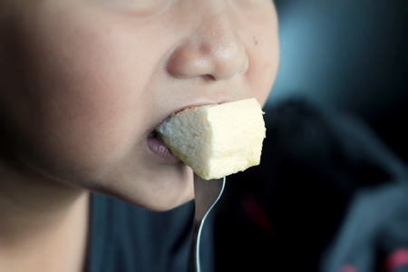 The boy eating bread butter topped with custard deliciousの写真素材