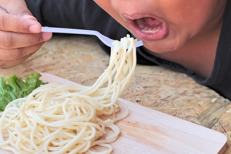 The boy eating pasta spaghettiの写真素材