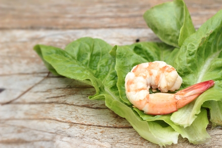 Shrimps with vegetables green leaves on wood background.の写真素材