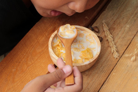 The boy eating corn flake with milk.