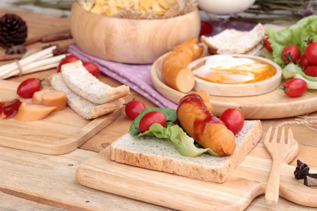 Breakfast with eggs, sausage, bread, salad vegetables and milk.の写真素材