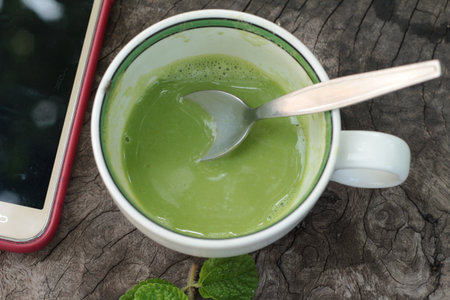 Green tea and milk on wood background