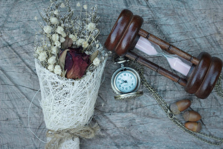 Antique pocket watch and hourglass with dried flowers
