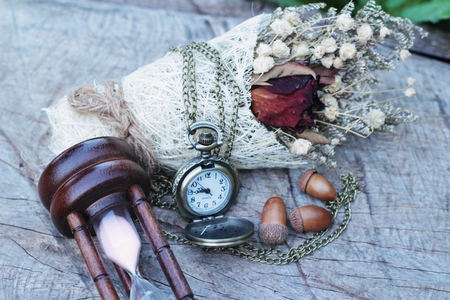 Antique pocket watch and hourglass with dried flowersの写真素材