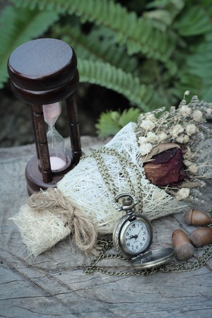 Antique pocket watch and hourglass with dried flowersの写真素材