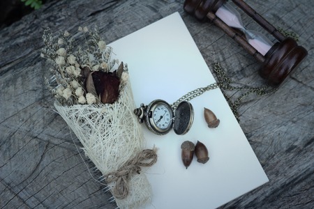 Antique pocket watch and hourglass with dried flowersの写真素材