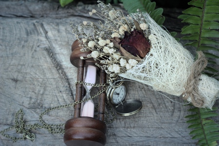 Antique pocket watch and hourglass with dried flowersの写真素材