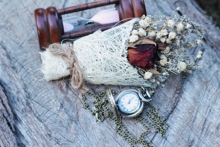 Antique pocket watch and hourglass with dried flowersの写真素材