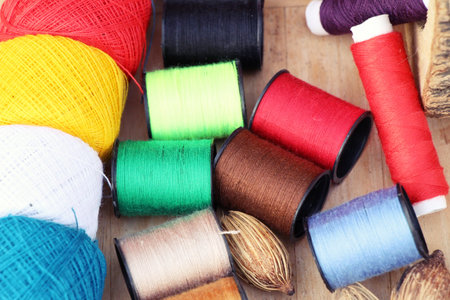 Colorful thread for sewing on wood background