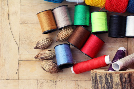 Colorful thread for sewing on wood background