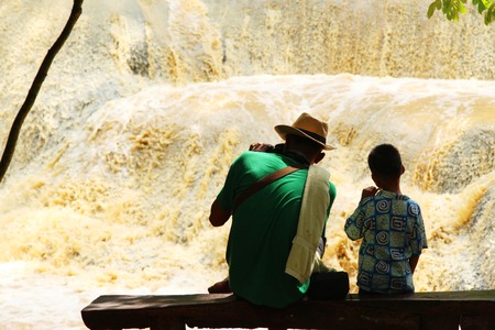 Waterfall landscape with man and boy in natureの写真素材