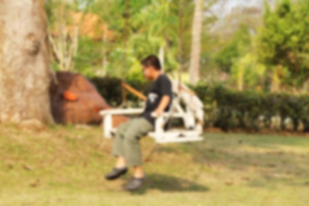 Blurred children playing swing hanging on treeの写真素材