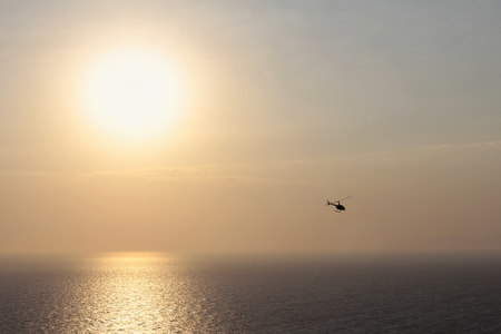 Little helicopter at orange sunset on islandの写真素材