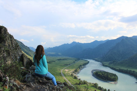 Woman sitting on a hill, looking at Island on the river Katun at summer day. Trip on Altai Republic, enjoyment of natureの写真素材
