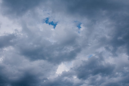 glowy dark clouds with blue gaps of clear sky. sky light