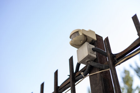 Small automatic street lamp connected to residential building communications. White flashlight with twelve diodes fixed to a metal fence outside with brightness and time adjustment.の写真素材