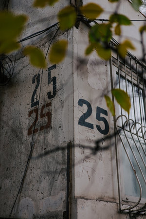 House numbering 25. The number twenty five is painted using a stencil three time on a gray wall on the corner of the house, near window with bars.の写真素材