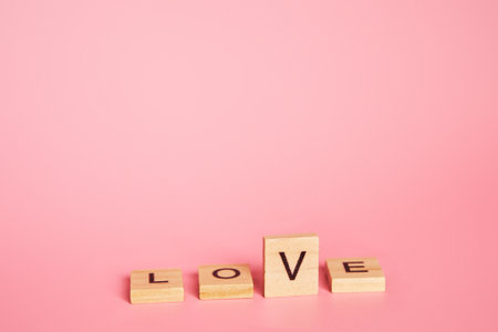 Love is a choice concept, letter v like a tick. The word love made up of individual wooden letters on a pink background with copy space. Valentines Day, 14th of February date.の写真素材