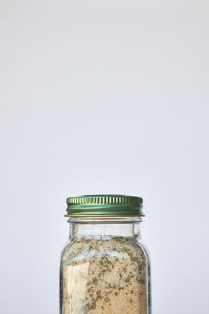 Jar of garlic, salt and herbs seasoning. close-up Glass container with closed green aluminum lid on...