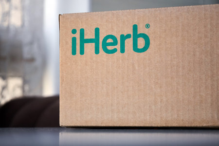 Brown Cardboard box with green logo inscription iHerb at home, on table. Online ordering, shopping, purchasing vitamins and cosmetics. Receiving the parcel. Bishkek, Kyrgyzstan - 8 Dec 2023のeditorial素材