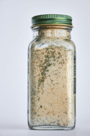 Jar of garlic, salt and herbs, Organic seasoning. close-up Glass container, closed green aluminum...
