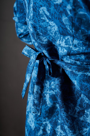 Blue dress fabric belt tied with a bow at the back. Women's clothing item made of thick cotton fabric close-up. Tailored clothingの写真素材