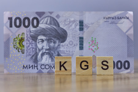 Inscription KGS with one thousand Kyrgyz soms, selective focus on wooden blocks. paper money, banknote. Currency in Kyrgyzstan, 1000 somの写真素材