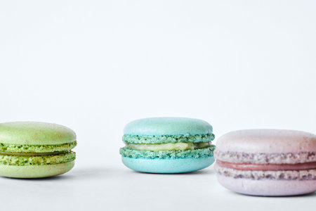 Three colorful French Macarons on gray background, cakes with different flavors, mint, apple,...
