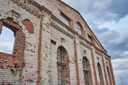 Abandoned destroyed brick building built in 1912. Wall with windows of old facility industrial...