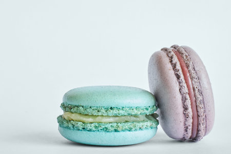Two colorful French Macarons, cakes with different flavors, mint, apple, current flavor. dessert, macaroons aquamarine, green, purple color. Copy space for text, close upの写真素材