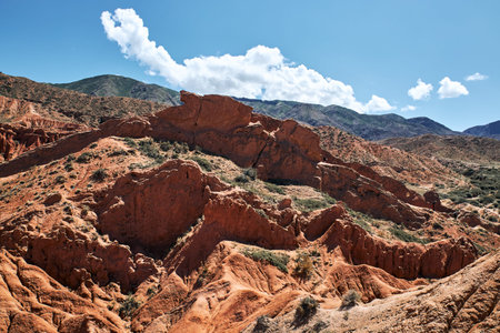 Striking landscape features expansive hills with vibrant hues of red, orange, tan, characteristic of...