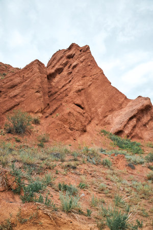 Sandstone red rocks. Sheer cliffs subject to erosion. Travel destination, famous landmark Kyrgyzstan, Central Asia. Rock formation, natural landscape, Konorchek canyon, hiking trekking areaの写真素材
