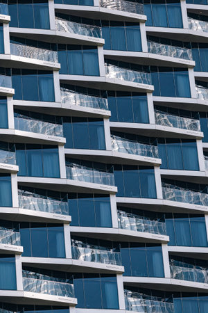fragment of apartment building with similar floor to ceiling windows and glass balconiesの写真素材