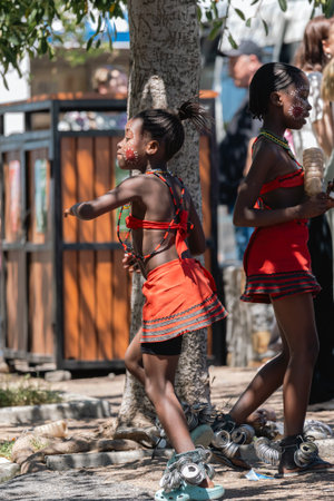 Two african girls in traditional costume dancing outdoors for tourists. Cultural performance for donation, childhood poverty. Cape Town, South Africa - 22 OCT 2023のeditorial素材