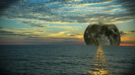 A composite of the moon setting in the sea with clouds   の写真素材