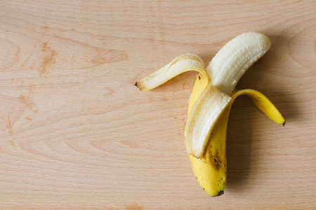 ripe peel banana on wooden cutting board top viewの写真素材