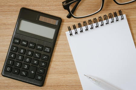 calculator, notepad ,pen and eyeglasses on wooden background. business finance conceptの写真素材