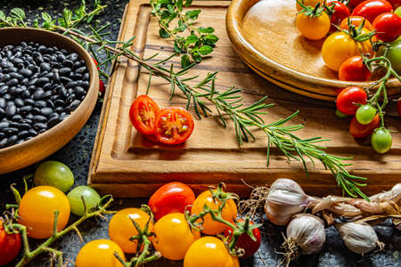 Fresh organic vegetables and ingredients on a wooden cutting boardの写真素材