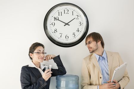 Male and female businesspersons talking under clock. Horizontally framed shot.の写真素材