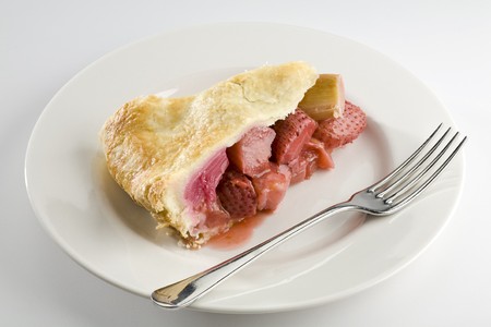 Slice of strawberry and rhubarb pie on white plate with forkの写真素材