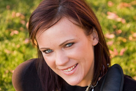 A young woman smiling while sitting in the grass.
