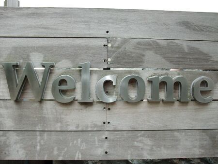 A metal Welcome sign panel  on timber boardの写真素材