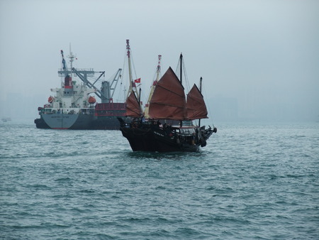 HONG KONG CHINA 6 FEBRUARY 2010 traditional wooden sailboat and Cargo ship sailing in Hong Kong.のeditorial素材